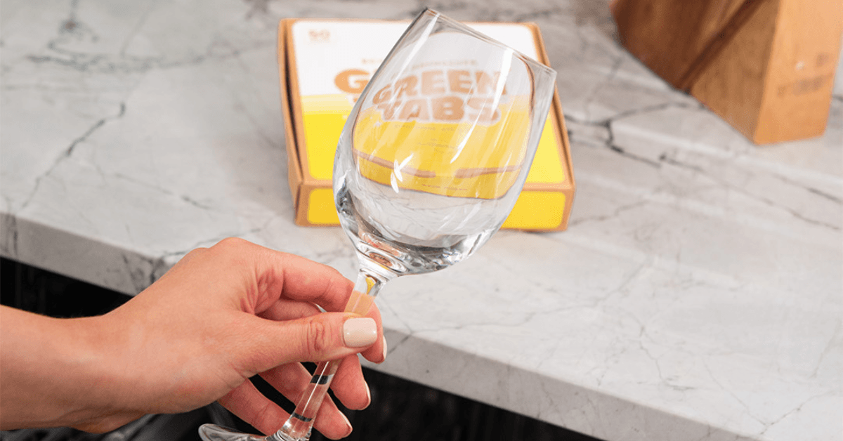 clean wine glass being removed from dishwasher after cleaning with dishwasher greentabs