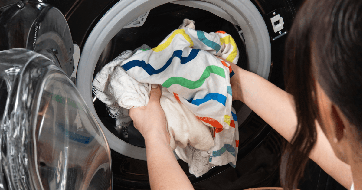 clothes being put into washing machine with laundry detergent greensheets