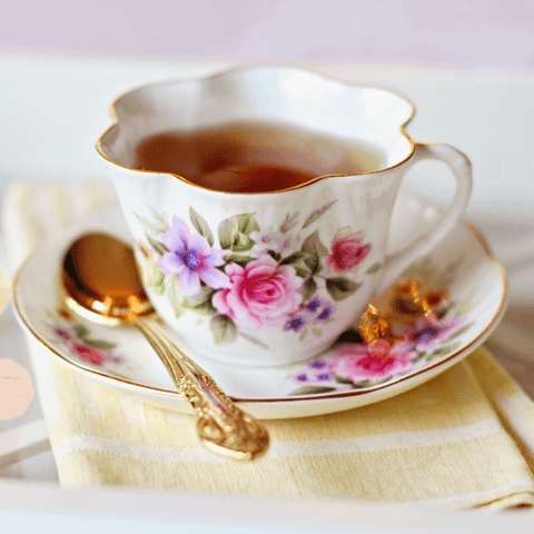 porcelain tea cup with flower print and golden spoon