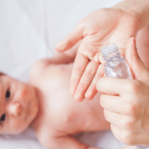 baby oil dispersed onto hand with baby in background