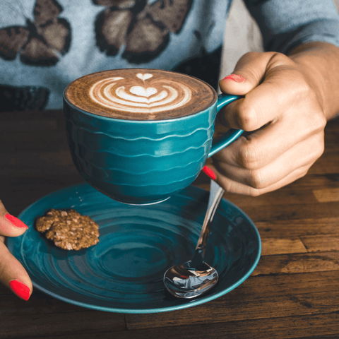 women holding blue coffee cup with coffee foam art