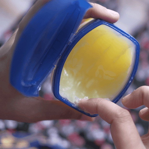 finger scooping vaseline out of vaseline packaging