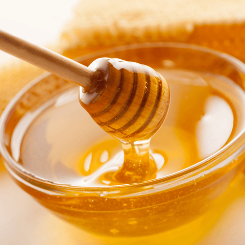 honey in glass dish dripping of honey spoon