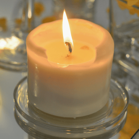 lit white candle on glass dish