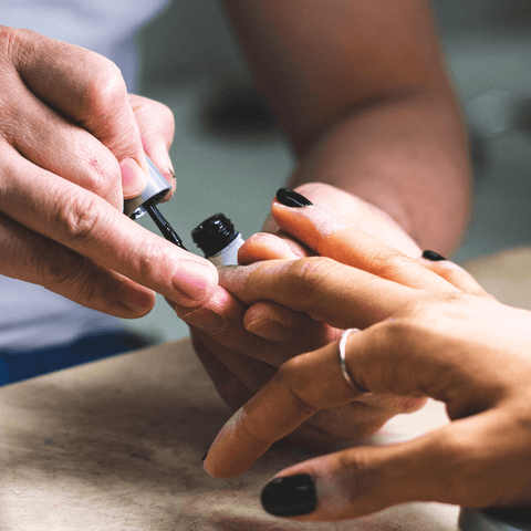 man applying black nail polish onto women hands