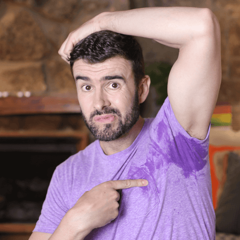 man in purple shirt gesturing to his underarm sweat stain