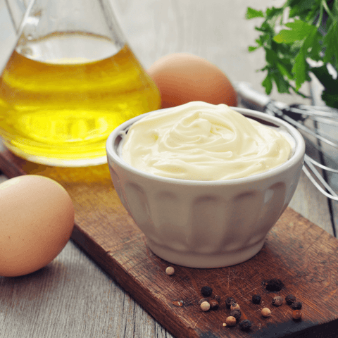mayonnaise in ceramic dish next to mayonnaise ingredients eggs and oil