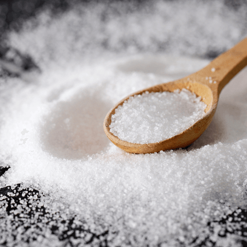 salt flakes surrounding wooden spoon