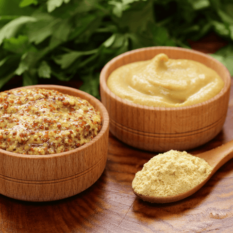 various mustard kinds in wooden dishes with mustard powder on wooden spoon