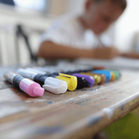 various colours of permanent marker with child in background