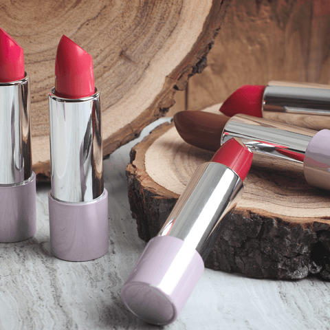 various red lipsticks scattered infront of wooden backdrop