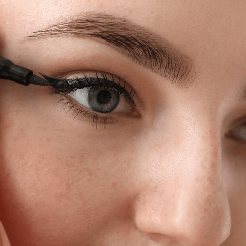 women applying black eyeliner onto eyelid