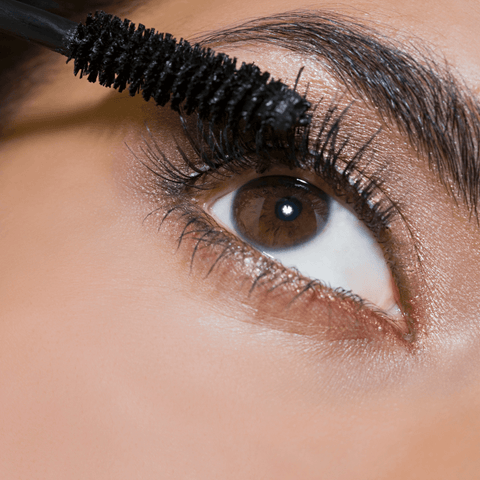 women applying black mascara onto lashes