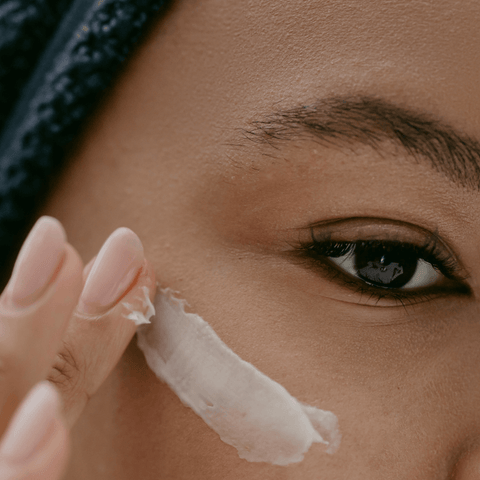 women applying facial moisturisers onto cheek