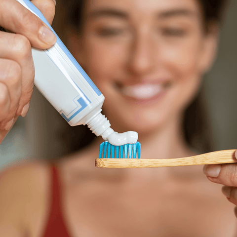 women applying toothpaste to toothbrush
